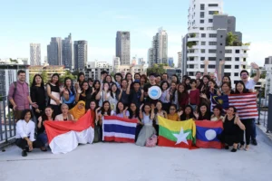 Programme participants smiling in front of a camera with the YSEALI logo and their respective country flags